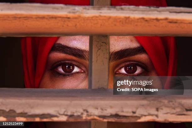 Liza Anvary, an Afghan refugee, poses behind a wooden window pretending to be in prison to represent the situation of women in her country. Liza...