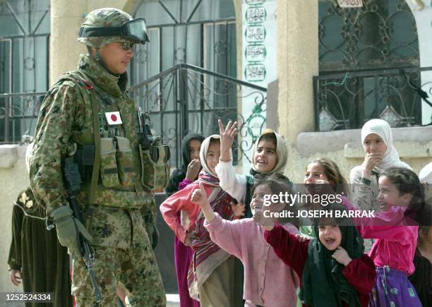 Iraqi girls give the thumbs-up at a Japanese Self Defence Force soldier standing guard outside a school in the village of Khodr near Samawa some 200...