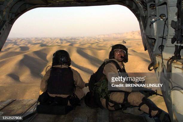 Crossing by air over hills into Afghanistan from Tajikistan, United States Special Operations soldiers keep watch from the open back end of a US Army...