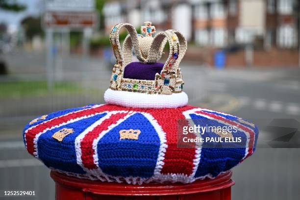 Photograph taken on May 2, 2023 shows a knitted crown displayed on a post office box next, in Rhyl, north Wales, ahead of the coronation ceremony of...