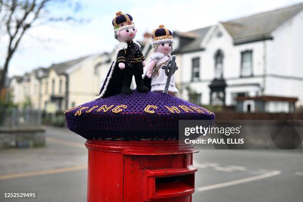Photograph taken on May 2, 2023 shows a knitted Britain's King Charles III and Britain's Camilla, Queen Consort displayed on a post office box next,...