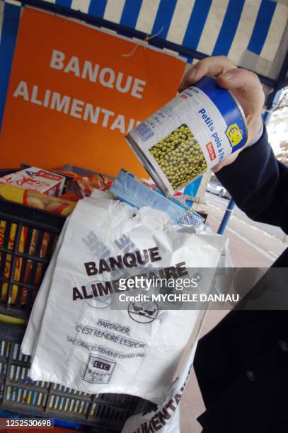 Une personne dépose une boite de conserve, le 24 novembre 2006 devant une grande surface à Caen, dans le cadre de la collecte annuelle des Banques...