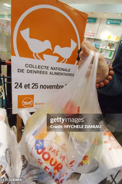 Une personne dépose un sac rempli de provisions, le 24 novembre 2006 dans une grande surface à Caen, dans le cadre de la collecte annuelle des...