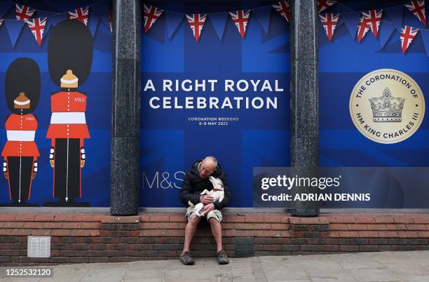Man poses with his dog in his arms in front of a decorated front window in the high street, in Windsor, on May 2 ahead of the coronation ceremony of...