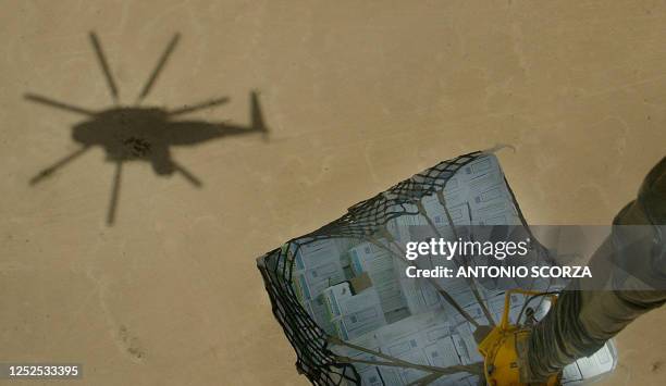 The shadow of a US Marine C853 helicopter is seen below on the desert landscape 26 May 2004, while transporting a pallet with supplies between the...