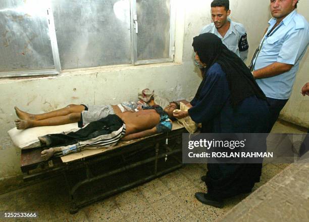 The mother of Adris Othamn, a ten year-old victim of an Iraqi mortar attack, covers his face as he lies dead at the Kindi Hospital in Baghdad, 27...