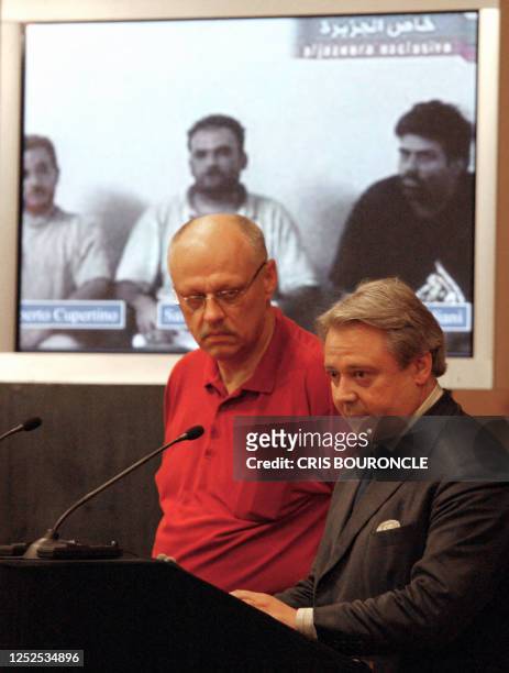Standing in front a projected image showing three Italian hostages from left to right: Umberto Cupertino Salvatore Stefio and Maurizio Agliana...