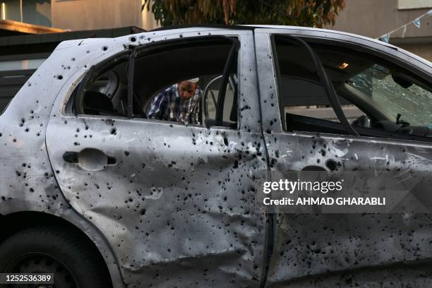 Man looks at a damaged car in the southern Israeli city of Sderot on May 2 following a flare-up between the Israeli military and Gaza militants. -...