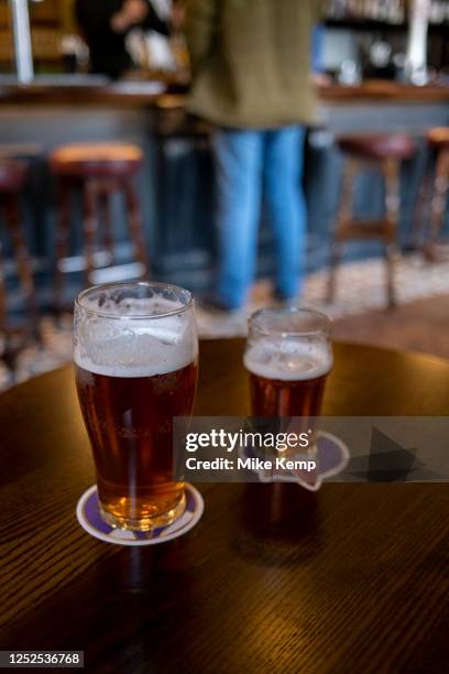 Pint and a half of English ale on a pub table on 12th April 2023 in Birmingham, United Kingdom. Beer prices in the UK have been on the rise with...