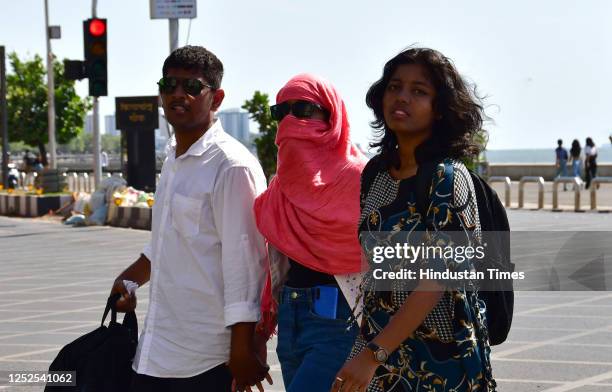 People cover themselves in the sweltering heat, at Marine Drive, on May 2, 2023 in Mumbai, India.