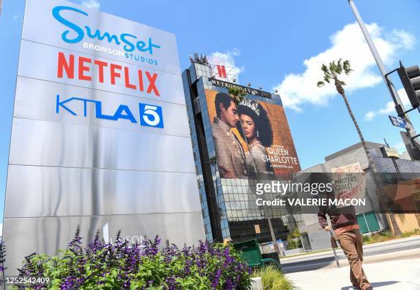 Screenwriter on strike walks by the Netflix sign on Sunset Blvd, on May 02, 2023 in Los Angeles, California. - More than 11,000 Hollywood television...