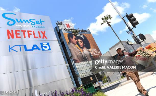 Screenwriter on strike walks by the Netflix sign on Sunset Blvd, on May 02, 2023 in Los Angeles, California. - More than 11,000 Hollywood television...