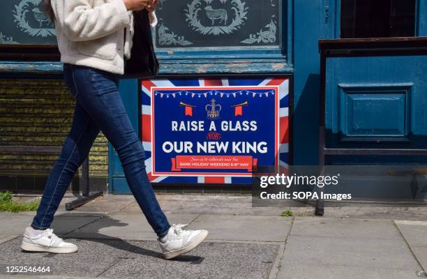 Pedestrian walks past a sign at a pub in Central London inviting people to raise a glass for the new king ahead of the coronation of King Charles III...