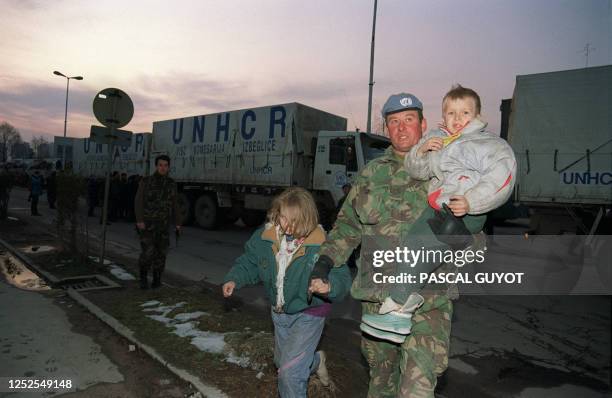 Soldier carries two refugee children from the Srebrenica area, 29 March 1993 in Tuzla. More than 2000 Moslems have been evacuated by the UN troops...