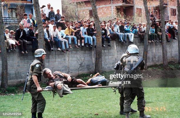 Badly injured Bosnian is being carried away on a stretcher by three Canadian UNPROFOR soldiers as residents look on, in Srebrenica, 25 April 1993, on...