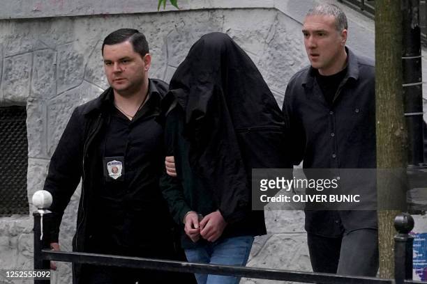 Police officers escort a minor, a seventh grade student who is suspected of firing several shots at a school in the capital Belgrade on May 3, 2023....