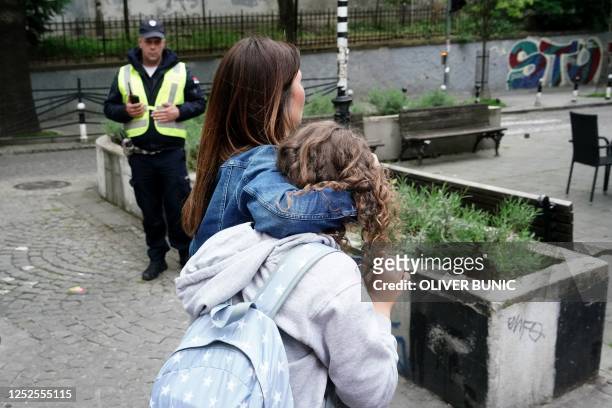 Parent escorts her child following a shooting at a school in the capital Belgrade on May 3, 2023. - Serbian police arrested a student following a...