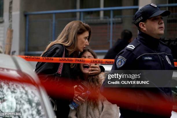 Parent escorts her child following a shooting at a school in the capital Belgrade on May 3, 2023. - Serbian police arrested a student following a...