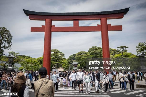 People cross a street outside of Tsuruoka Hachimangu shrine in Kamakura city of Kanagawa prefecture on May 3, 2023.