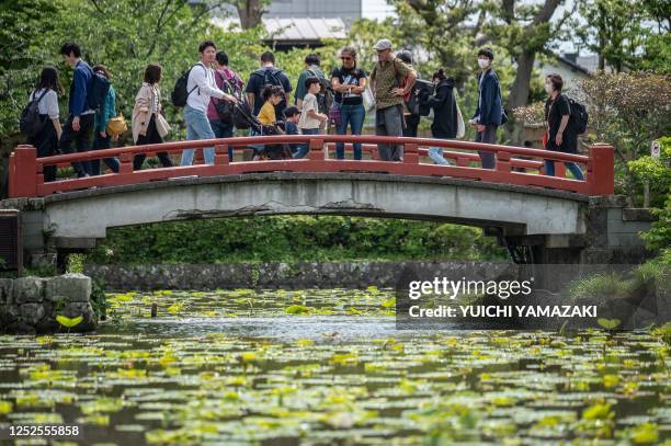 People cross a bridge at Tsuruoka Hachimangu shrine in Kamakura city of Kanagawa prefecture on May 3, 2023.