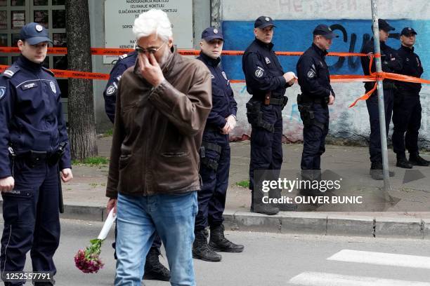 Man cries as he walks past police officers guarding the school entrance following a shooting at a school in the capital Belgrade on May 3, 2023. -...