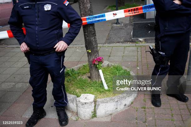 Flowers is placed for the victims as police officers guard the scene after a shooting at a school in the capital Belgrade, on May 3, 2023. - The...