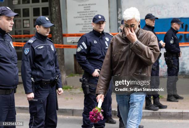 Man reacts as he walks past police officers blocking a street near the 'Vladislav Ribnikar' elementary school on May 3, 2023 in Belgrade, Serbia. At...