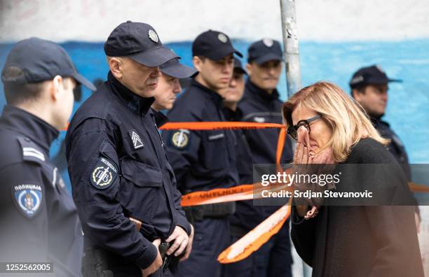 Woman reacts as she walks past police officers blocking a street near the 'Vladislav Ribnikar' elementary school on May 3, 2023 in Belgrade, Serbia....