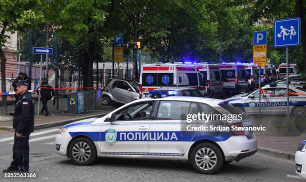 Ambulance cars stand ready as police officers block a street near the Vladislav Ribnikar elementary school on May 3, 2023 in Belgrade, Serbia. At...
