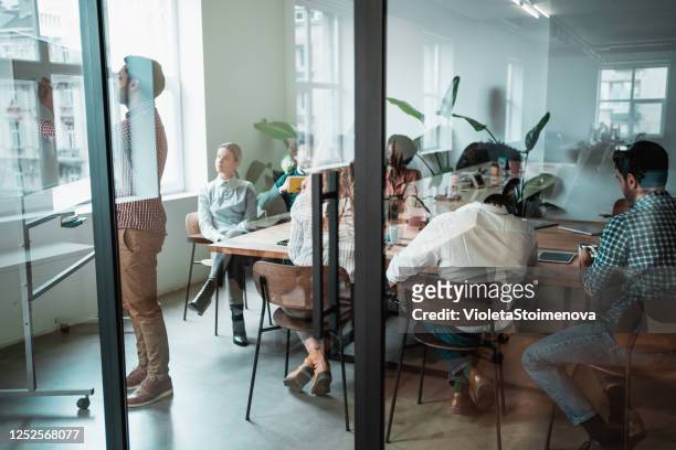young entrepreneur presenting his coworkers new business strategy on a meeting. - advertisement stock pictures, royalty-free photos & images