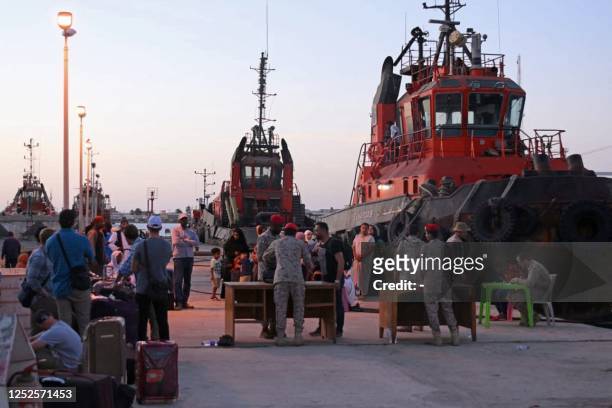 People wait with their luggage on the dockside of Port Sudan on May 3, 2023 ahead of their evacuation by sea amid ongoing deadly clashes between...
