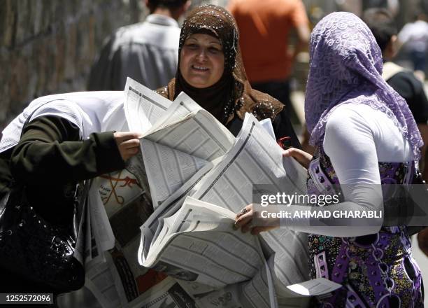 Palestinian women read the high school general certification exam results listed in the local news paper after they were published today by the...