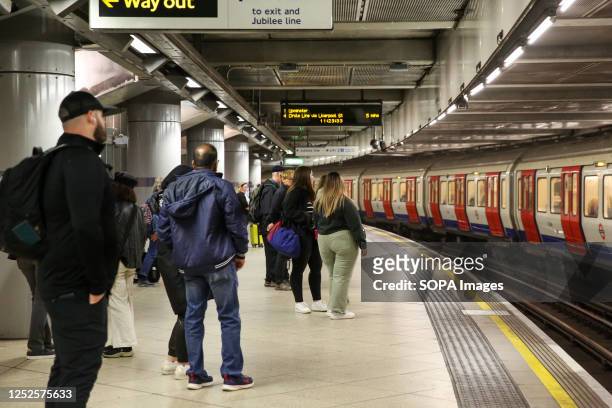 Passengers on Westminster underground station platform wait for a train to arrive.