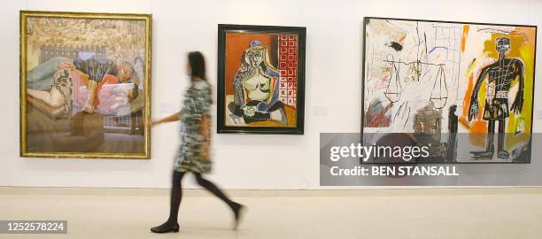 Visitor walks past paintings by Lucian Freud 'Ib and her husband,' Pablo Picasso 'Femme accroupie au costume turc' and Jean-Michel Basquiat '...