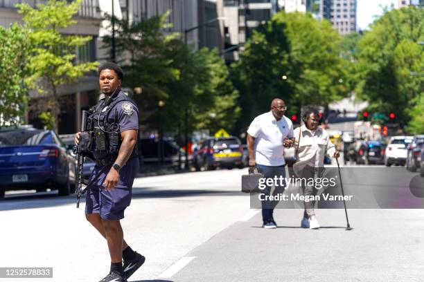 Couple crosses the street as police officers work the scene of a shooting at a Northside Hospital medical facility on May 3, 2023 in Atlanta,...