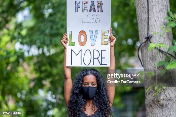 young african american woman holding protest sign - black civil rights stock pictures, royalty-free photos & images