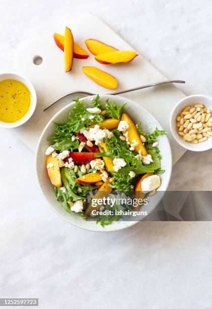 ensalada de otoño de lechuga iceberg, espinacas, melocotón y queso de cabra en un plato rústico blanco sobre fondo de mármol con espacio de copia - queso de cabra fotografías e imágenes de stock