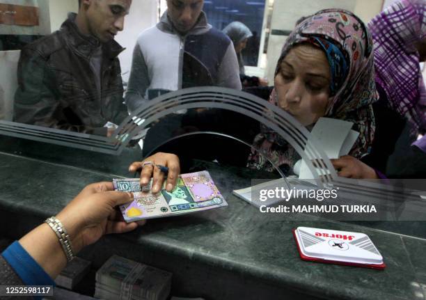 Libyan bank cashier gives a client outdated bank notes, which had been removed from circulation several years ago and reissued recently by the...