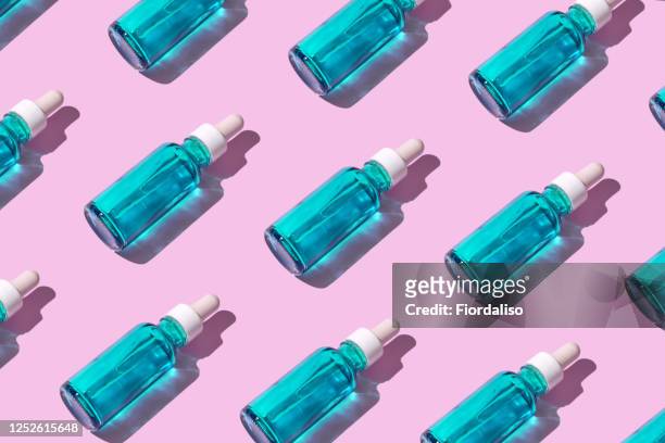 transparent liquid dropper 
and blue bottle on pink pastel background - enzymes cosmetics stockfoto's en -beelden