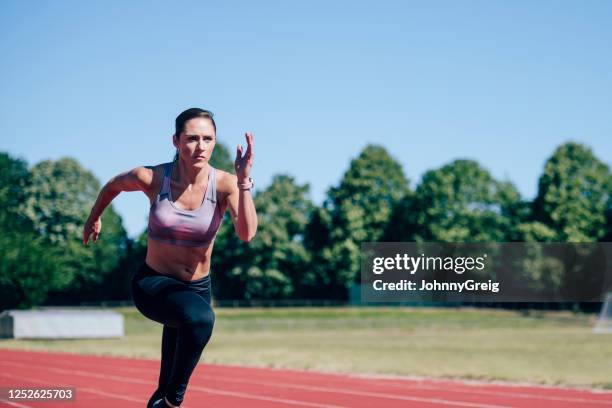 mid adult caucasian female athlete sprinting on sports track - female sprinting stock pictures, royalty-free photos & images