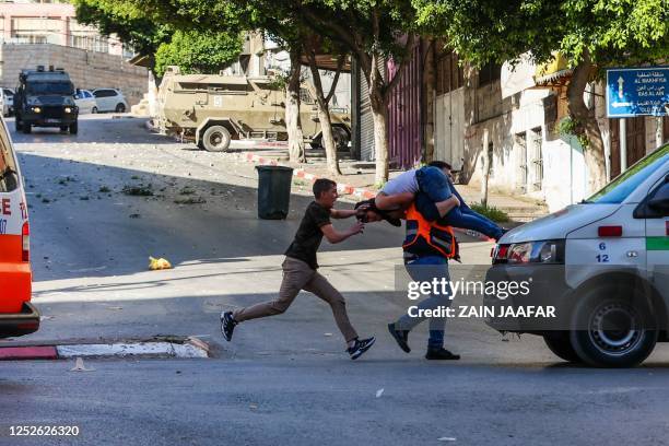 Medic carries an injured man to safety during clashes between Israeli forces and Palestinians following an Israeli army raid in the occupied West...