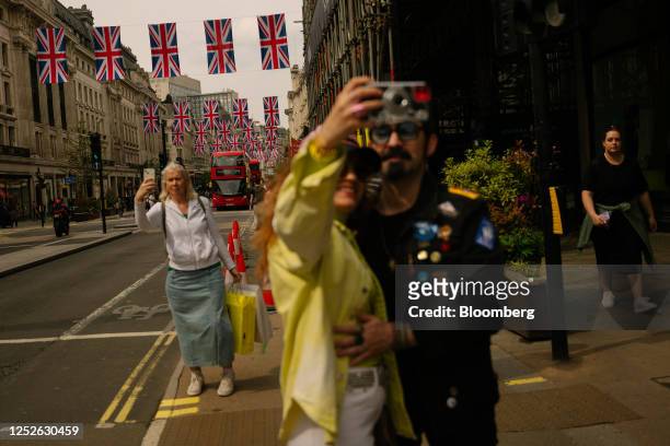 Shoppers take selfies in front of Union flags on Regent Street, owned by the Crown Estate, in London, UK, on Sunday, April 30, 2023. King Charles...