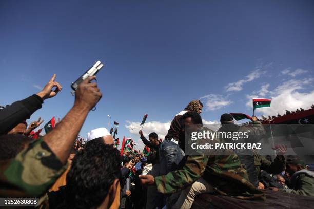 Libyans shout slogans while carrying the coffin of a comrade killed the day before in the battle for Ras Lanuf on a pick-up truck on March 11, 2011...
