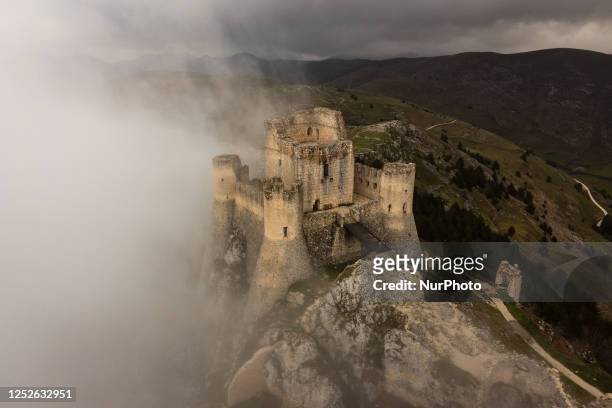 An aerial drone view shows Rocca Calascio castle surrounded by fog and clouds in Calascio, Abruzzo, Italy, on May 4, 2023. Rocca Calascio castle is...