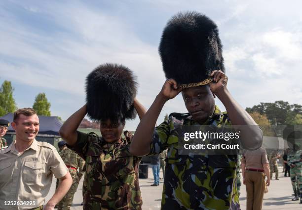 Kenyan soldiers try on bearskin hats belonging to British Guardsmen after a military parade for representatives of the Commonwealth taking part in...