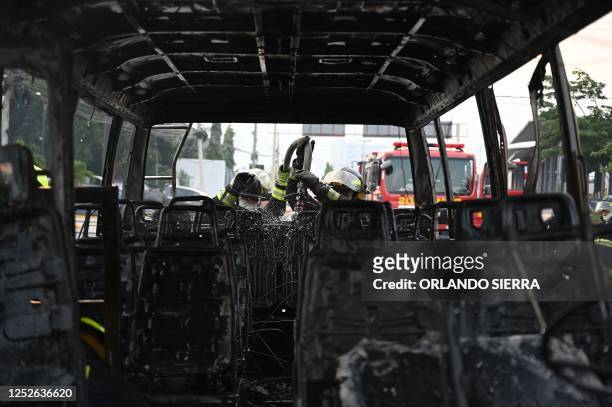 Firefighters work to extinguish the fire of a bus that was burned by alleged gang members in the vicinity of the National Autonomous University of...