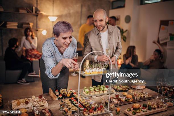 corporate colleagues making gourmet food decisions at office party - party food and drink stock pictures, royalty-free photos & images
