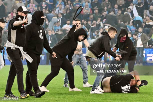 Udinese fans attack a Napoli fan as spectators invade the pitch at the end of the Italian Serie A football match between Udinese and Napoli on May 4,...