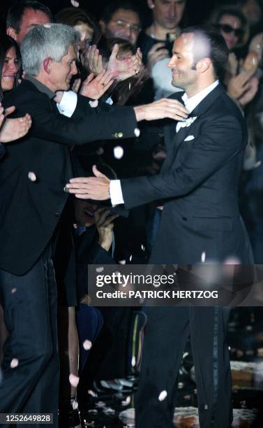 Designer Tom Ford embraces his partner Richard Buckley, editor in chief of "Vogue Hommes International" as he acknowledges applause on the catwalk at...