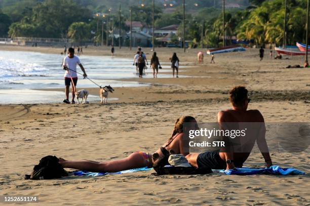 Tourists sunbath on the beach in the Pacific coastal town of San Juan del Sur, Nicaragua, on April 25, 2023. - Drawn to the natural beauty, security...